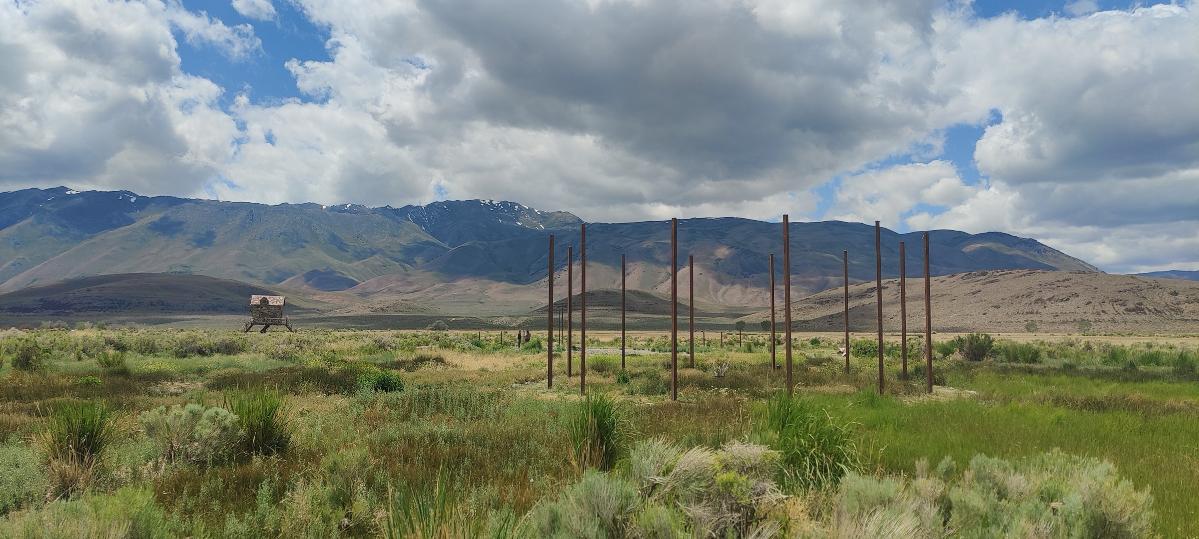 Survey poles marking out The Loop on the Fly Ranch plain, mountains behind